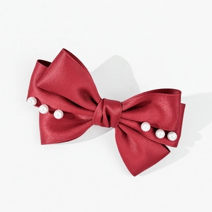 Détail d'un nœud papillon en satin rouge avec des bords en perles sur un fond blanc