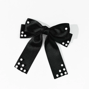 Détail d'un nœud à cheveux en satin noir orné d'élégantes perles blanches raffinées
