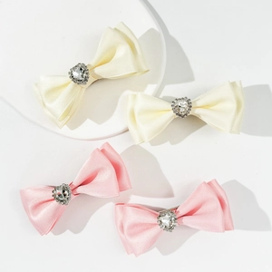 Dettaglio di fermagli per capelli in raso con cuori di strass scintillanti in rosa e bianco