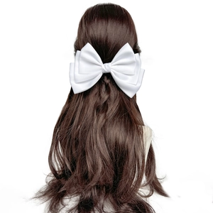 Detailed back view of a large white satin bow hair clip on long wavy brown hair
