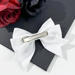 Dettaglio della clip in metallo argento su fiocco di raso bianco con rose rosse