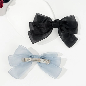 Detail showing the silver metal spring clip and sheer organza fabric of the bow hair clip
