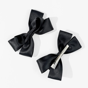 Detail von zwei schwarzen Satin-Schleifen-Haarspangen mit silbernen Entenschnabel-Clips