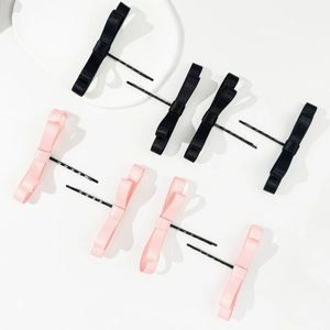 Vue détaillée d'un ensemble de 8 barrettes à nœuds en satin rose et noir sur plateau blanc