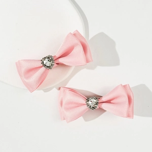 Dettaglio di fermagli per capelli con fiocco rosa e strass a cuore con base in metallo
