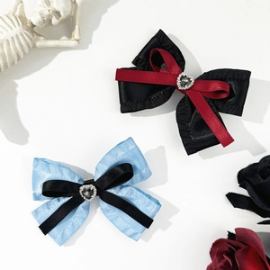 Detail of gothic style bow hair clips featuring heart rhinestones and layered ribbons