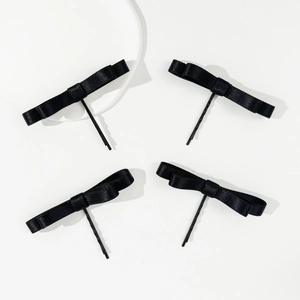 Vue détaillée de quatre barrettes à nœuds en satin noir sur des clips métalliques simples