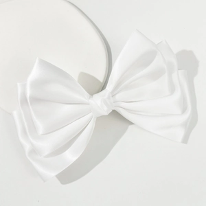 Detailed view of layered white satin bow hairclip with elegant glossy texture