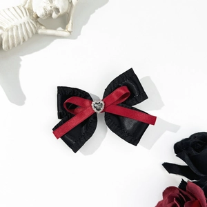 Macro detail of gothic style black and red ribbon bow with a crystal heart center
