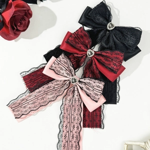 Detail of gothic lace bow hair clip with heart rhinestone and satin fabric texture