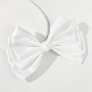 Elegant white satin oversized bow hair clip with multi-layered design on minimalist background