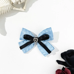 Blue and black bow hair clip featuring a centered crystal heart gem on a white background