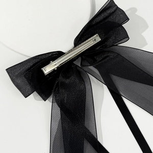 Detail of the metal duckbill clip attached to the black mesh bow hair accessory