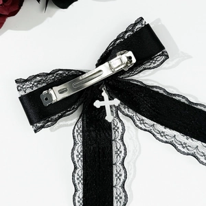 Détail du nœud en dentelle noire gothique avec croix argentée et pince à ressort en métal