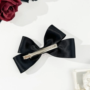Detailed close-up of a black satin bow hair clip featuring an elegant Gothic style design