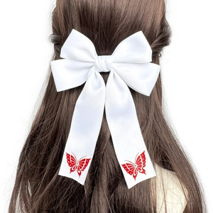 Nahaufnahme der weißen Satin-Haarschleife mit roten Schmetterlingsdrucken auf Bändern