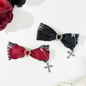 Close-up of gothic bow hair clips with red heart gems and silver cross charms