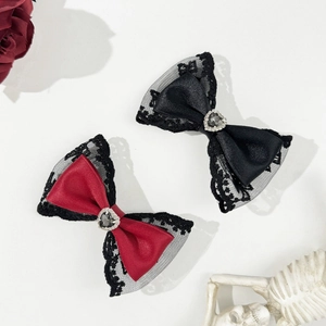 Detailed macro view of Gothic lace heart bow hair clips with red and black satin textures