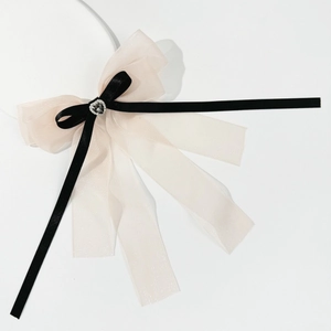 Detail of a mesh bow hair clip with black ribbons and a crystal heart center ornament