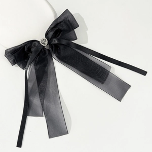Detail of black layered mesh bow hairpin with a sparkling rhinestone heart on white base