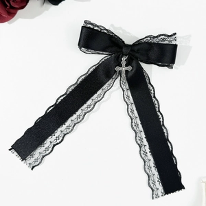 Détail du nœud en satin noir avec dentelle et pendentif croix gothique argentée