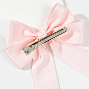 Detailansicht der rosa Satin-Schleife mit silberner Metall-Haarklammer auf weißem Hintergrund