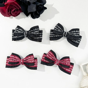 Detail of gothic style black and red striped bow hair clips with white script lettering