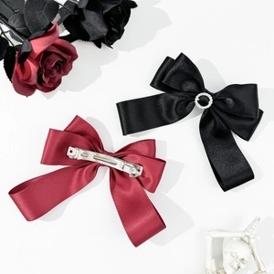 Detail view of red and black satin bow hair clips with crystal ring and metal spring clip