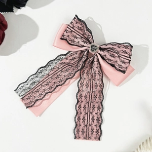 Detail of pink satin bow hair clip with black floral lace and a heart rhinestone center