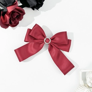 Elegant deep red satin bow hair clip with rhinestone center on white backdrop