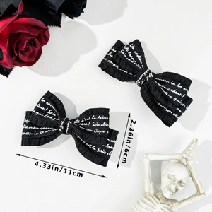 Detail view of 11cm x 6cm gothic black bow hair clips with white script text pattern