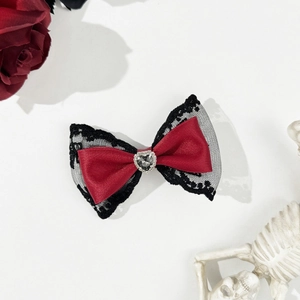 Close-up of gothic burgundy bow hair clip with black lace and heart-shaped rhinestone
