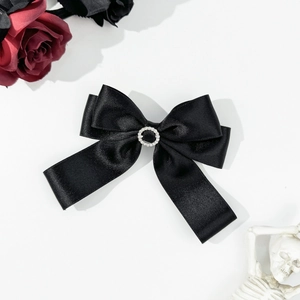 Close-up of black satin bow hair clip with central rhinestone ring in gothic style