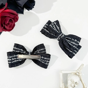 Detail view showing front and back of black gothic bow hair clips with letter print