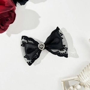 Gothic black lace bow hair clip with heart rhinestone center shown on white background