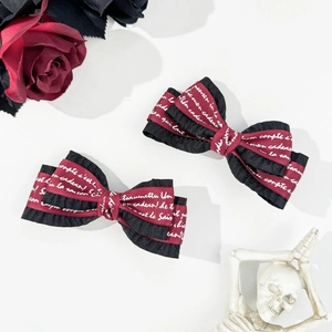 Gothic style bow hair clips with dark red ribbons and white letters on a clean background