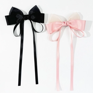 Detail view of elegant satin bow hair clips in black and pink with long flowing ribbons