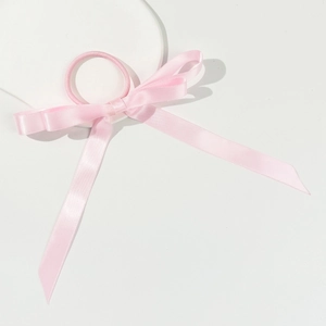 Dettaglio dell'elastico per capelli in raso rosa con fiocco su espositore in pietra