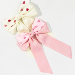 Détail de barrettes en satin avec cœurs rouges sur rubans crème et roses