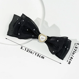Detail view of black triple-layer bow hair clip with heart pearl and rhinestones