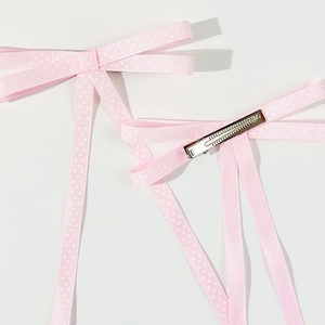 Dettaglio delle mollette per capelli a pois rosa con nastri lunghi e clip in metallo argento