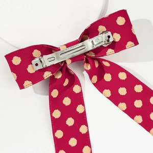 Close-up of vintage polka dot bow hair clip with ribbons and silver metal spring fastener