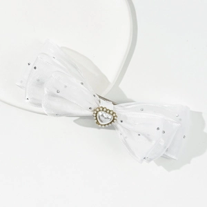 Detail of white satin three-layer bow hair clip with heart pearl and sparkly rhinestones