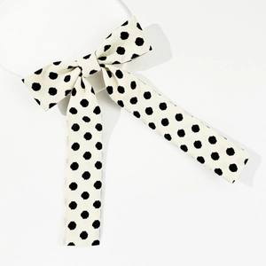 Vintage white polka dot bow hair clip with long ribbons on a minimalist background