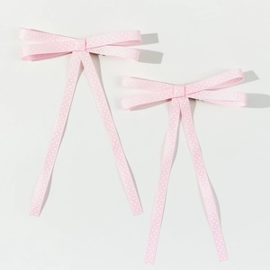 Dettaglio di fermagli per capelli a fiocco rosa a pois con lunghi nastri sottili