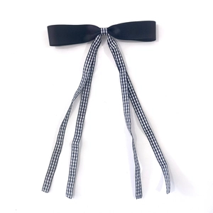 Close-up of black satin bow hair clip with vintage gingham ribbon streamers for hair styling