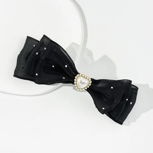 Macro detail of multi-layer black bow hair clip with heart-shaped pearl and rhinestones
