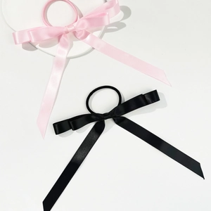 Elastici per capelli con fiocco in raso rosa e nero su vassoio in pietra bianca