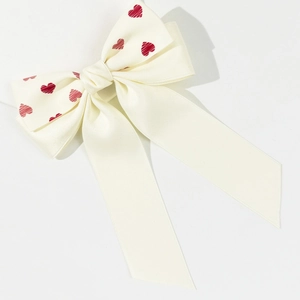 Détail d'un nœud papillon en satin crème avec cœurs rouges et longs rubans doux