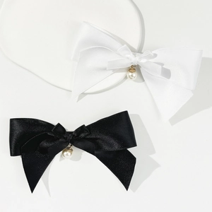 Detailed macro view of satin bow hair clips featuring black and white fabric with pearl drops